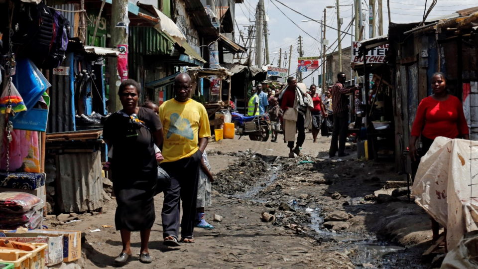 Residents walk along an alleyway with an open sewer at the Mukuru slum in Nairobi