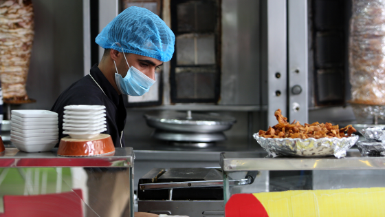 Restaurant worker wears mask as he prepares food