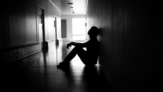 Silhouette of man sitting on walkway of residence building