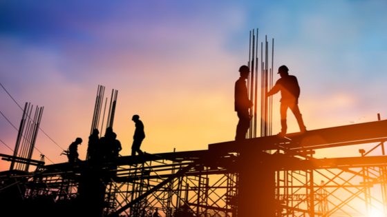 Silhouetted construction workers at sunset