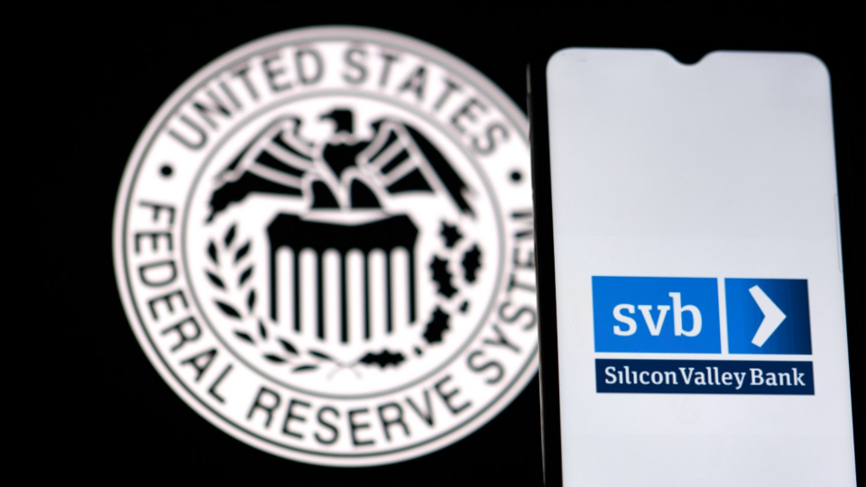 Silicon Valley Bank logo on phone screen with Federal Reserve logo displayed in the background