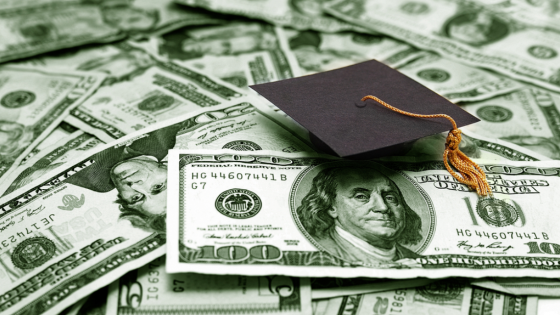 Small graduation cap on top of U.S. dollar bills