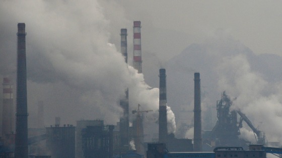 Smoke rises from chimneys and facilities of steel plants on a hazy day in Benxi