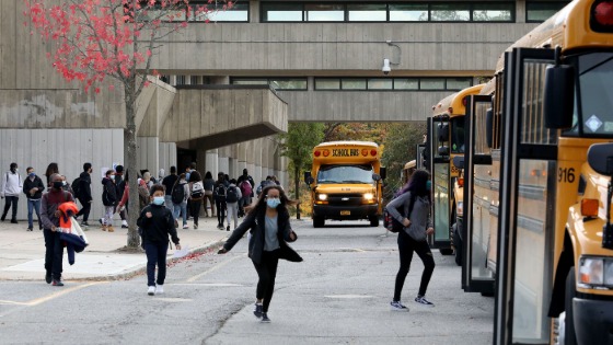 Students run toward their school busses after dismissal