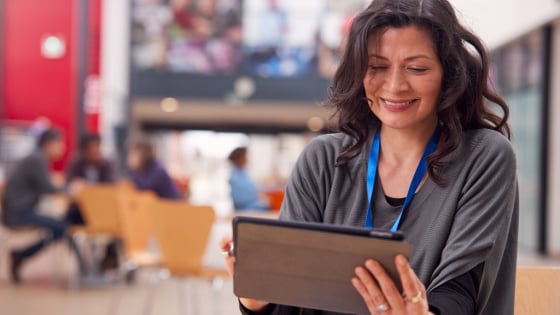 Teacher views tablet with class in background