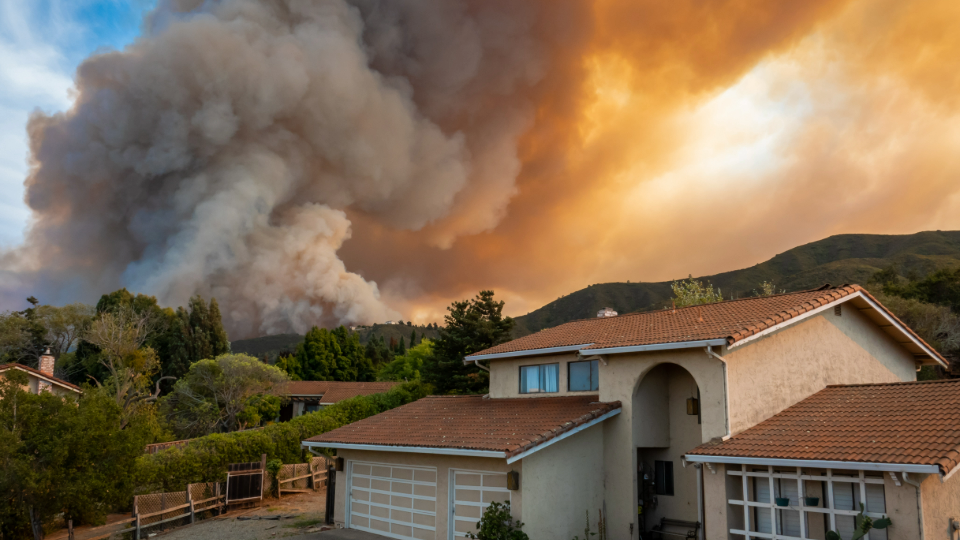 The California River Fire of Salinas fills the sky with dark smoke and flames as it burns close to a house