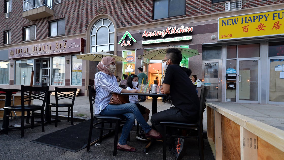 The Sukarmadijaya family sit dine al fresco at a table set up off the sidewalk in front of Awang Kitchen