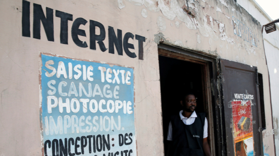 The owner of an internet cafe in Congo stands at the door of his business.