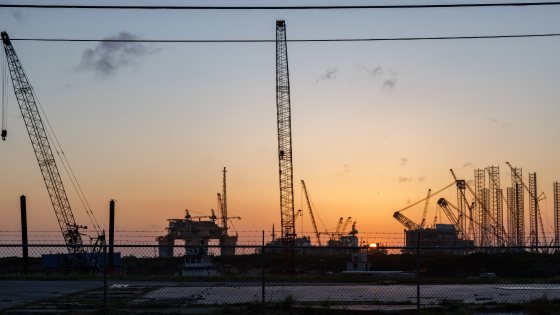 The sun sets beyond machinery at a Kiewit Offshore Services construction site in Ingleside