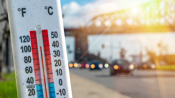 Thermometer in front of cars and traffic during heatwave