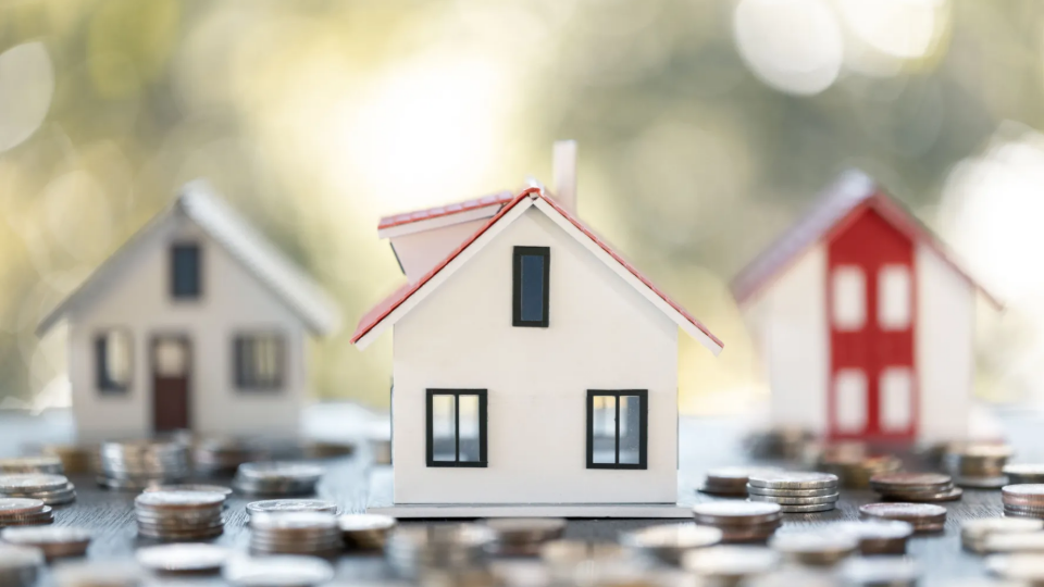 Toy houses with coins stacked around them