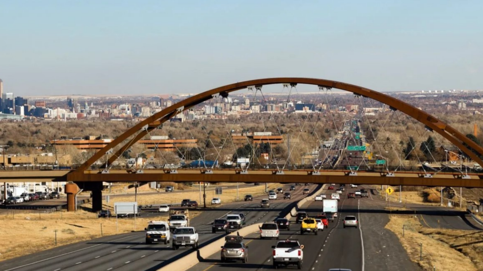 Traffic passes under a bridge that carries trains for public transit in the Denver metro area