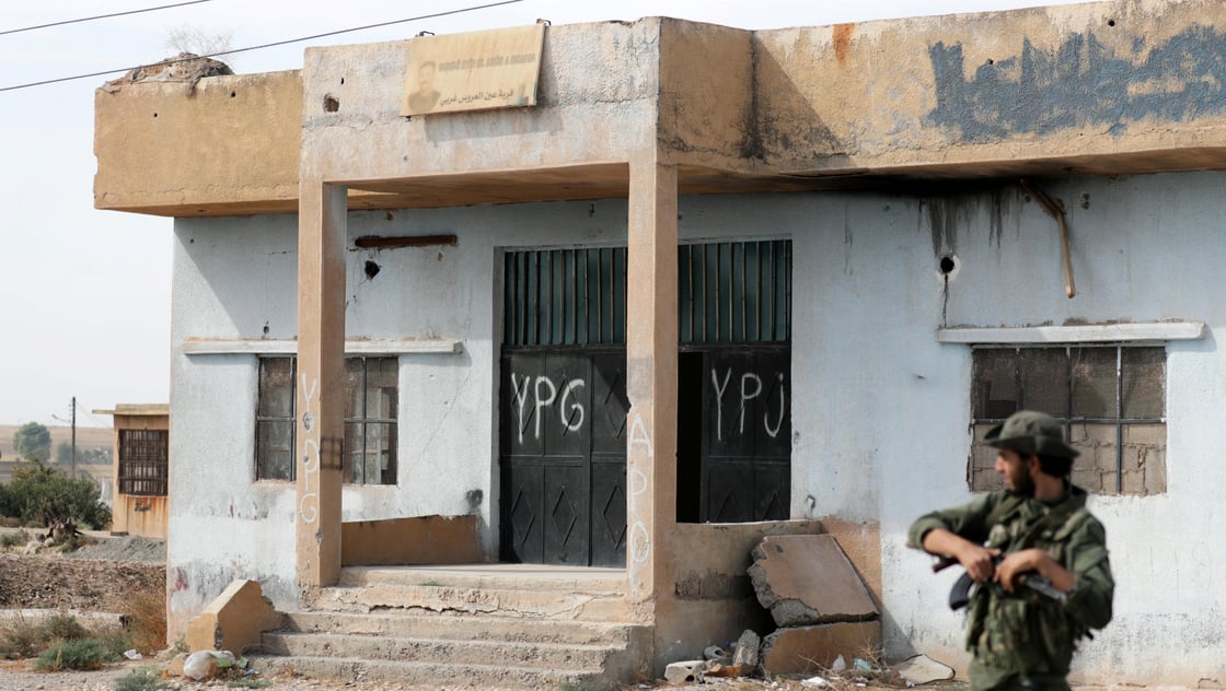 Turkey-backed Syrian rebel fighter stands near a former YPG office at the entrance of Tel Abyad