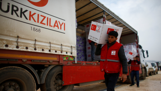 Turkish Red Crescent workers carry humanitarian aid at Kelbit camp, near the Syrian-Turkish border