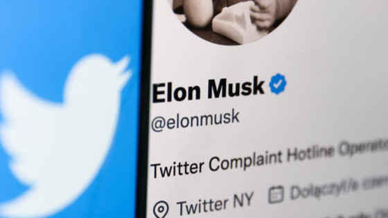 Twitter logo displayed on a phone screen and Elon Musks Twitter account displayed on a laptop screen