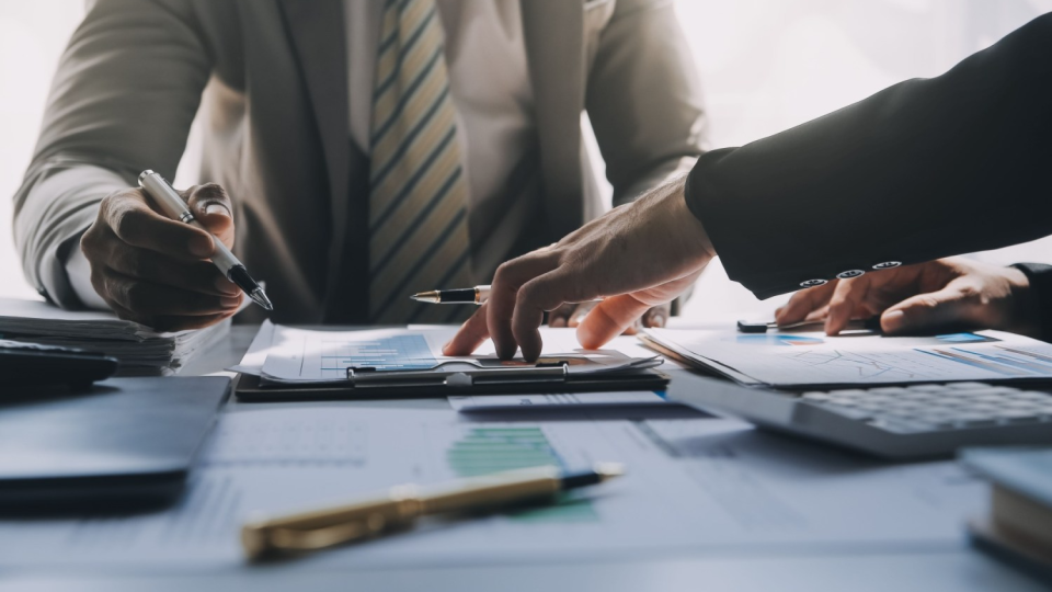 Two men in business suits signing financial documents.