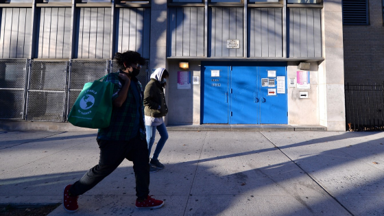 Two people walk past the closed side entrance of The International High School for Health Sciences