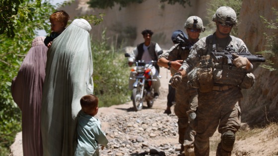 U.S. Army soldiers patrol in Mainjui as local women walk by in Arghandab valley in Kandahar p