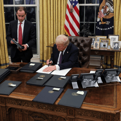 U.S. President Donald Trump signs documents as he issues executive orders in the Oval Office.