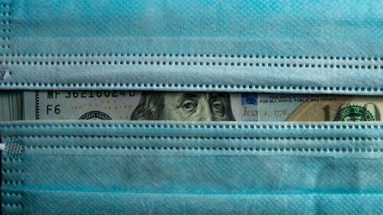 U.S. currency peeking out from behind two surgical masks