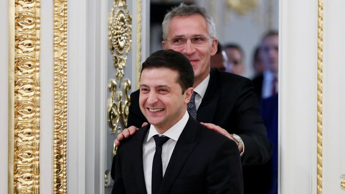 Ukrainian President Volodymyr Zelenskiy and NATO Secretary-General Jens Stoltenberg react while entering a hall following their talks in Kiev