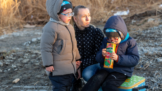 Ukrainian family waits for their relative after crossing into Poland