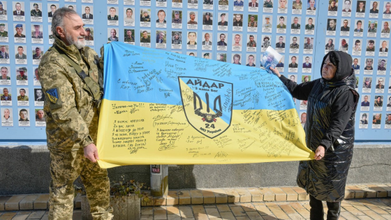 Ukrainians hold the flag of the Aidar battalion near the wall of memory