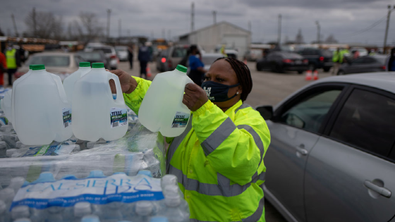 Volunteer Elizabeth Murray helps hand water to local residents at Butler Stadium