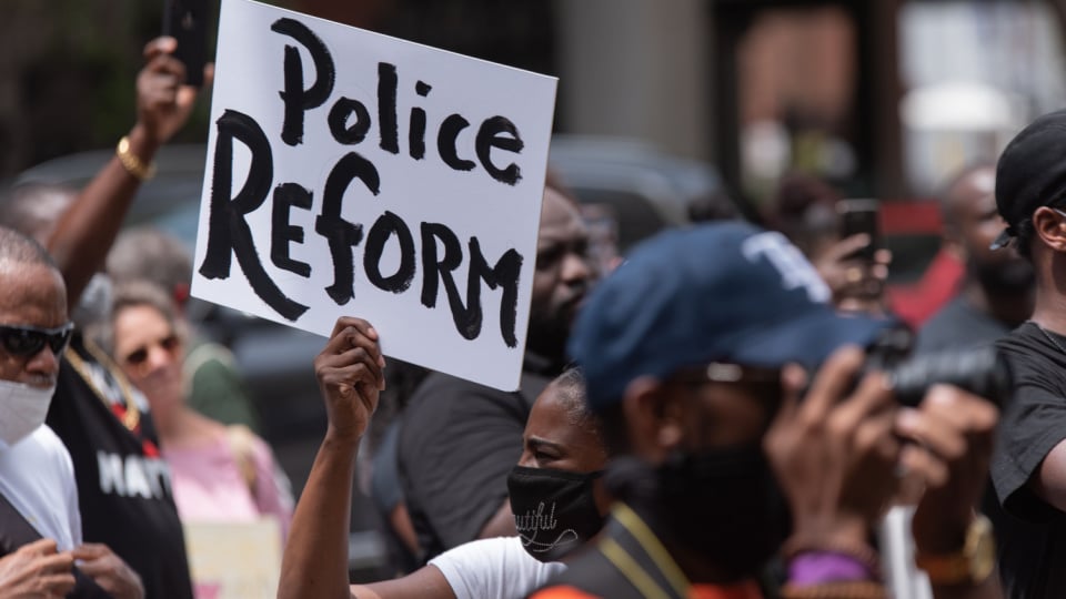Woman holds up Police Reform sign at protest.