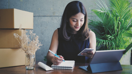 Woman looks at phone while taking notes