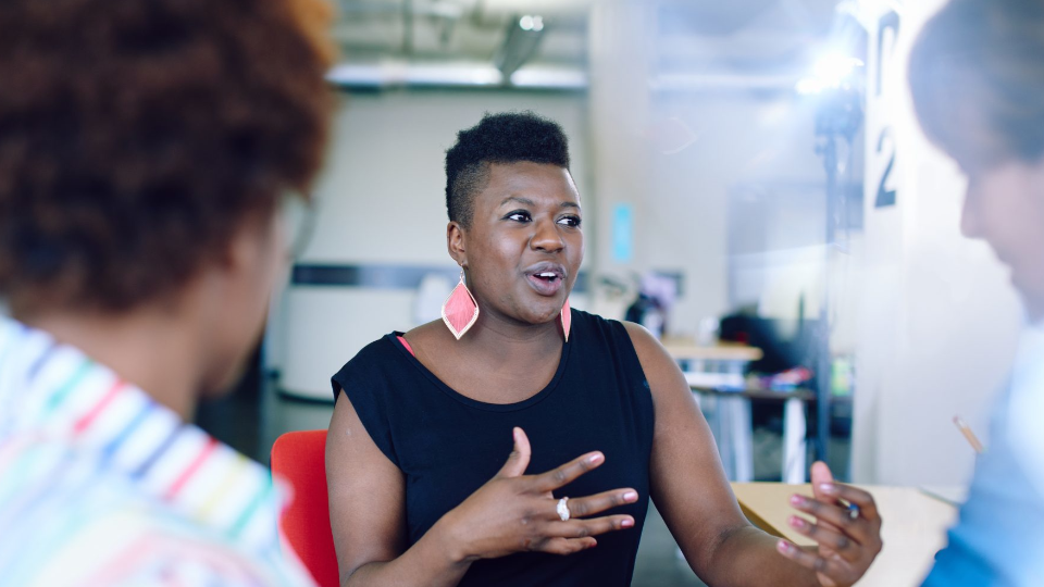 Woman speaks with business partners in an office room.