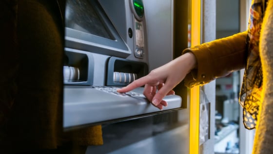 Woman uses keypad at an ATM to check her account