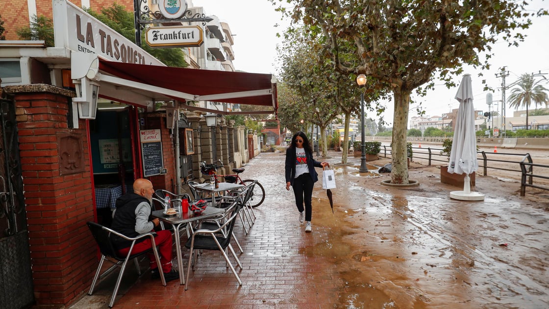 Woman walks on wet and muddy street after torrential rain in Spain