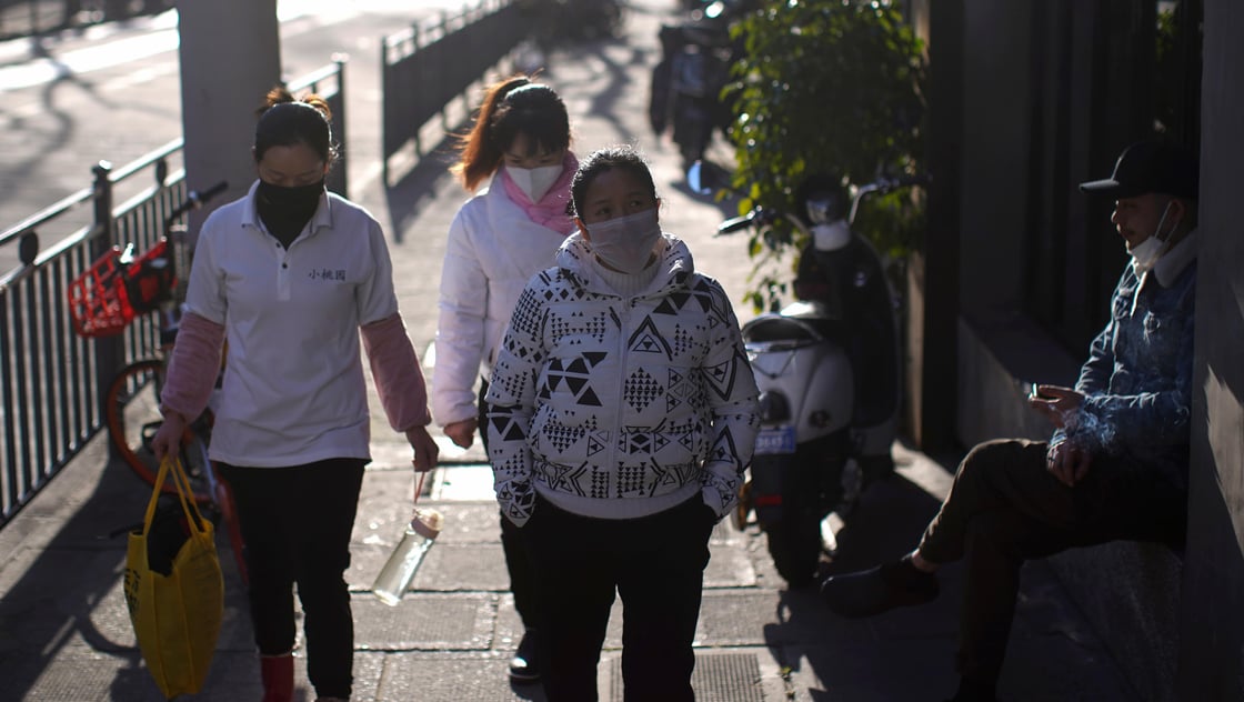 Women wearing masks walk in a street in Shanghai