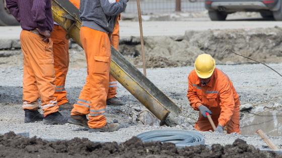 Worker leveling concrete poured from mixer on construction site