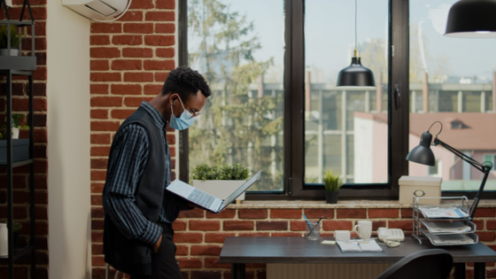 Worker wearing mask looks at laptop screen
