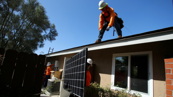 Workers install solar panel onto a roof in San Diego