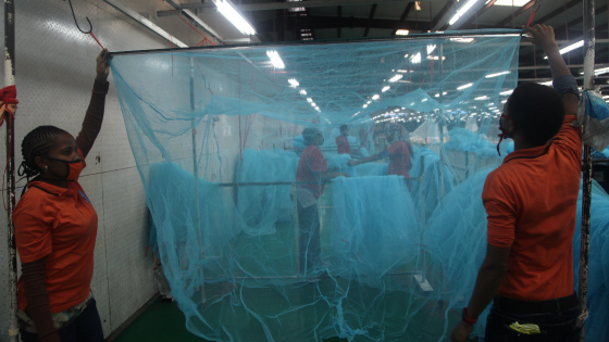 Workers look for abnormal holes in mosquito netting at the A to Z Textile Mills factory