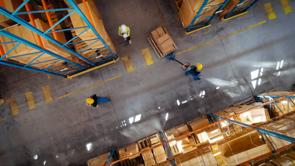 Workers move goods in a distribution center.