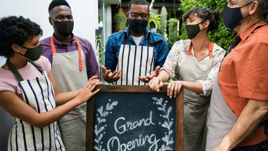 Workers stand around grand opening sign