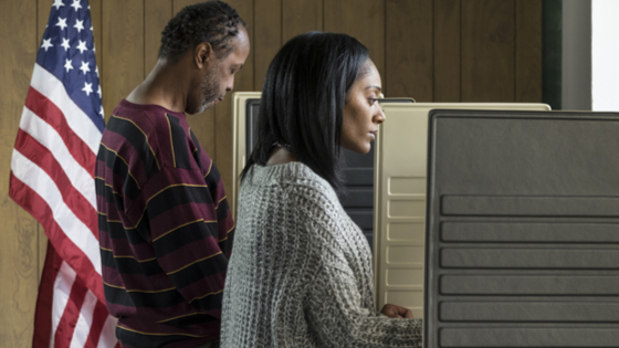 Young black woman and black male voting in a booth.