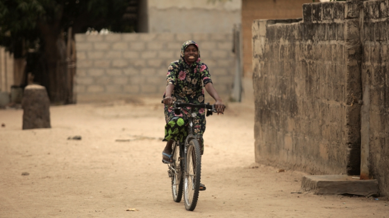 Young girl rides bicycle through village