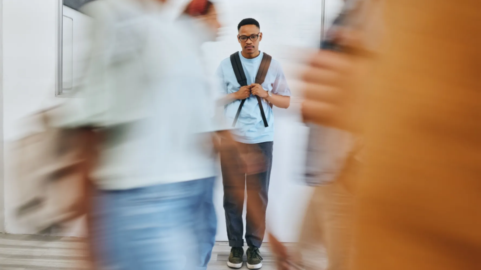 Young person appears subdued as people walk by