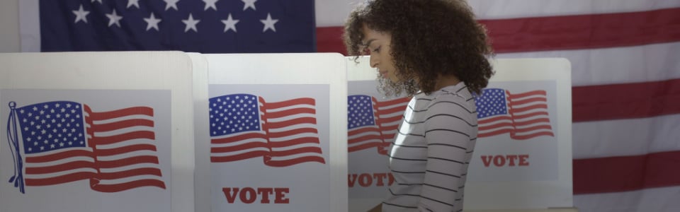 Young voter casts ballot at booth.