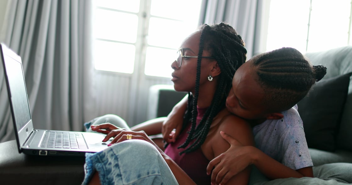 Overworked mother working from home using laptop and multi-tasking with child (Shutterstock)