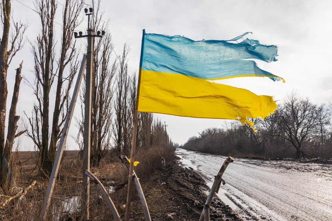 A torn but flying Ukrainian flag is seen along a road in the Donetsk region. (Shutterstock, Drop of Light)