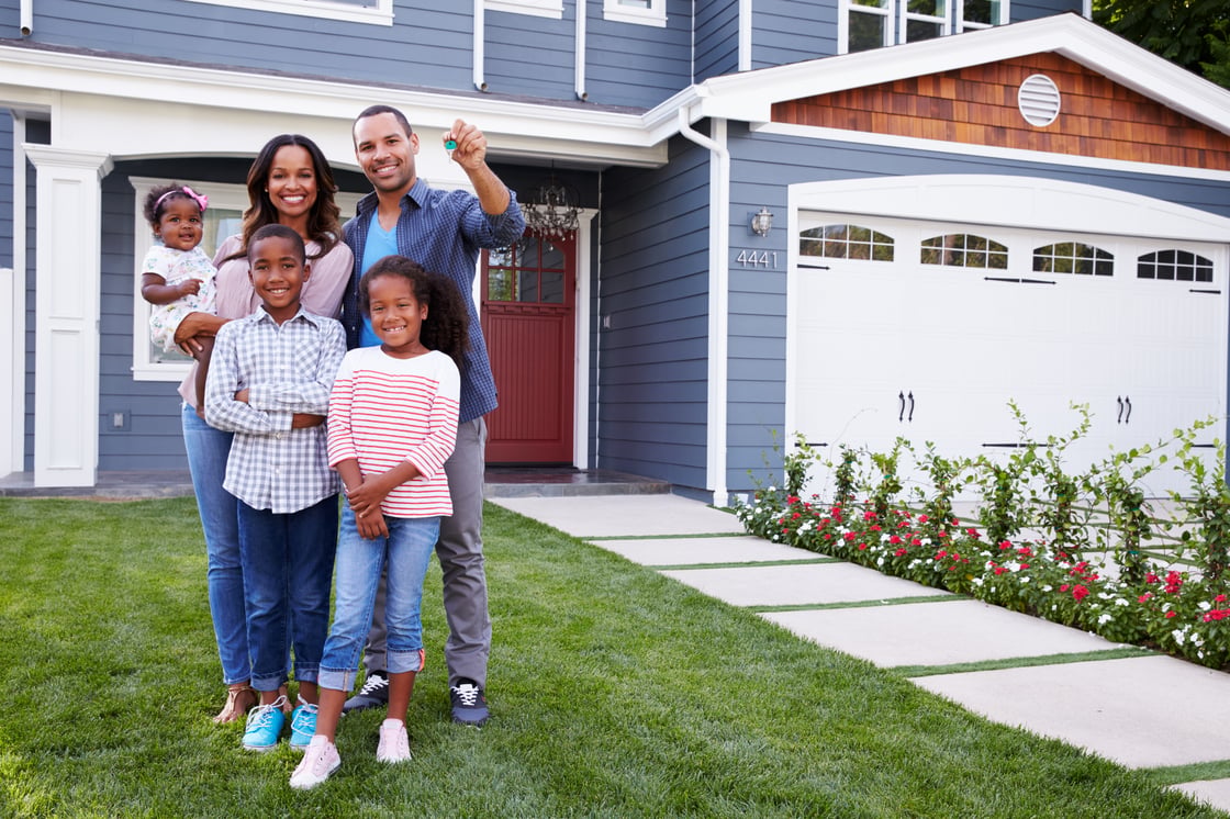 Happy black family standing outside their house, dad holding the key (Shutterstock)
